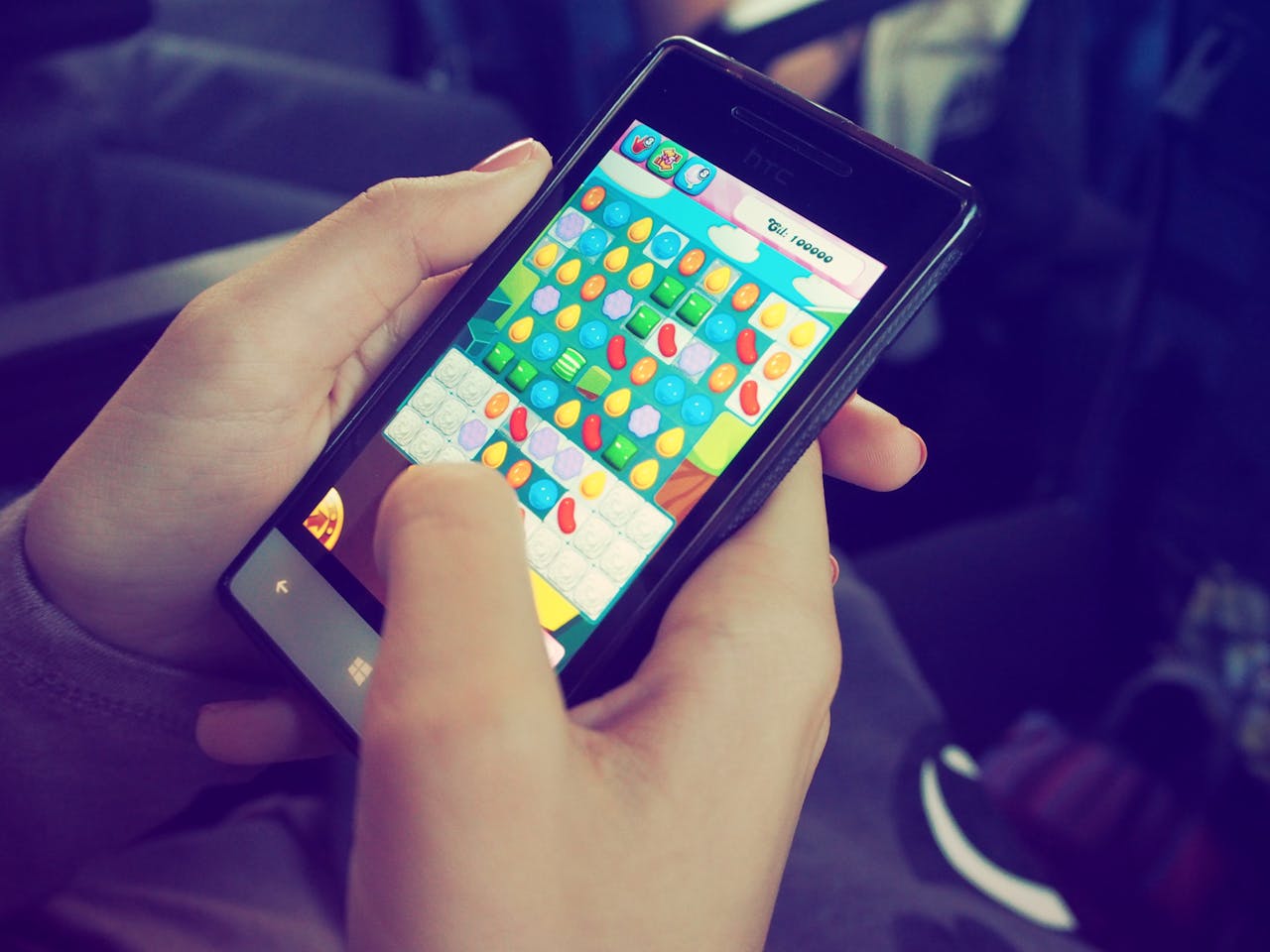 menu-06 Hands holding a smartphone with a colorful puzzle game on the screen, displaying modern technology.