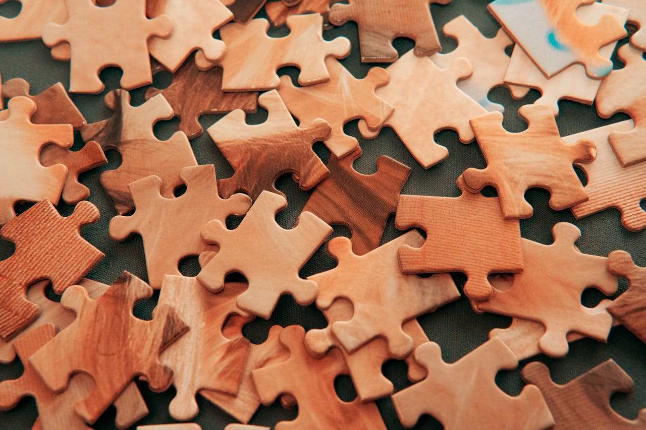menu-01 A close-up view of scattered wooden jigsaw puzzle pieces on a dark surface.